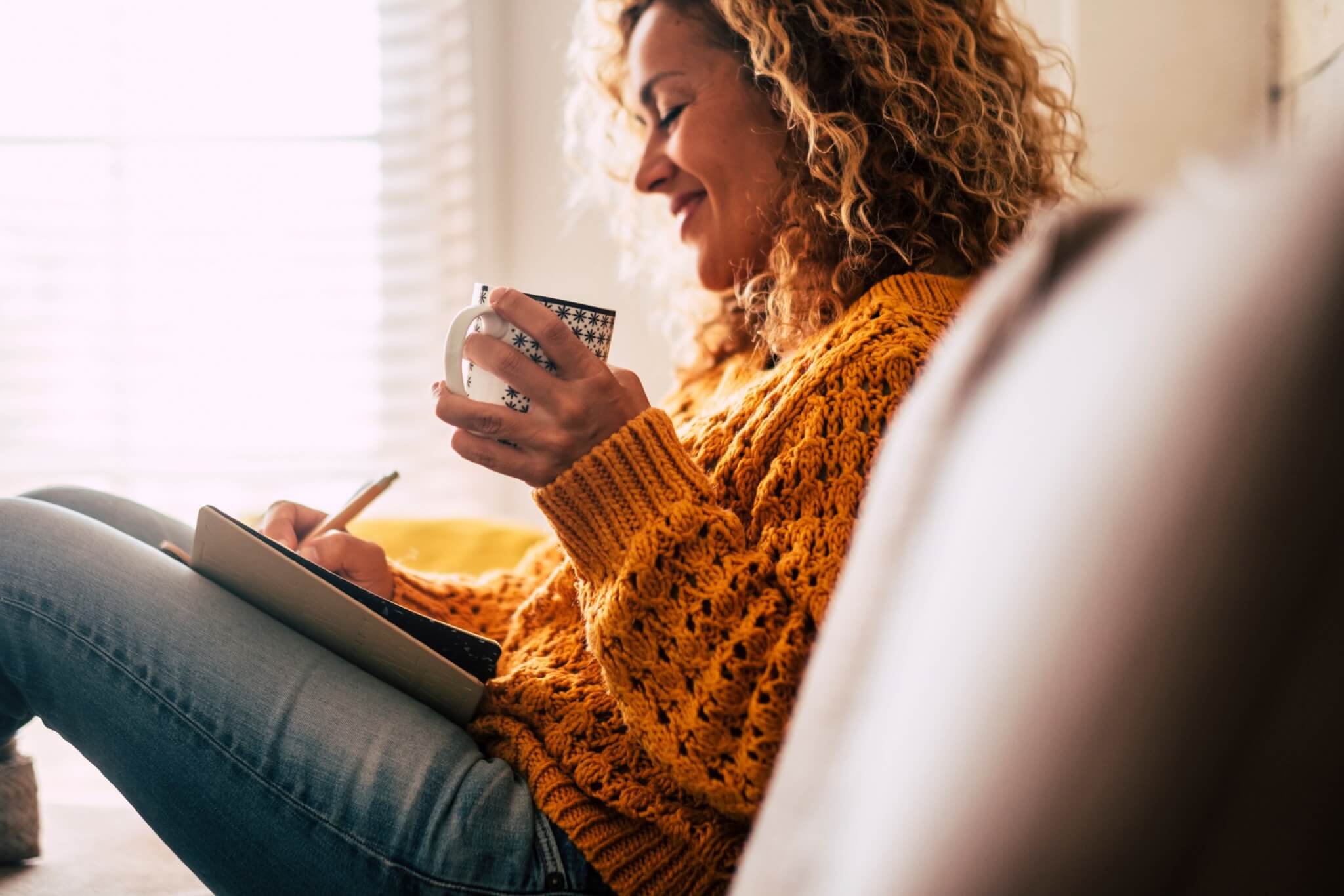 Woman writing in journal and drinking tea de-stress after work